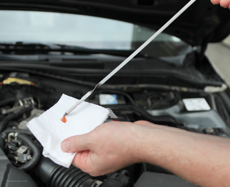 Mechanic checking automatic transmission fluid level on dipstick